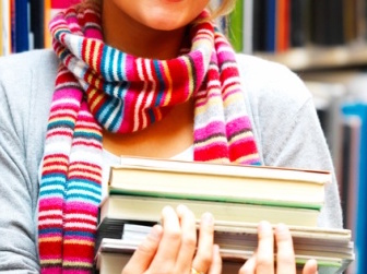 Pretty charming woman holding books in library